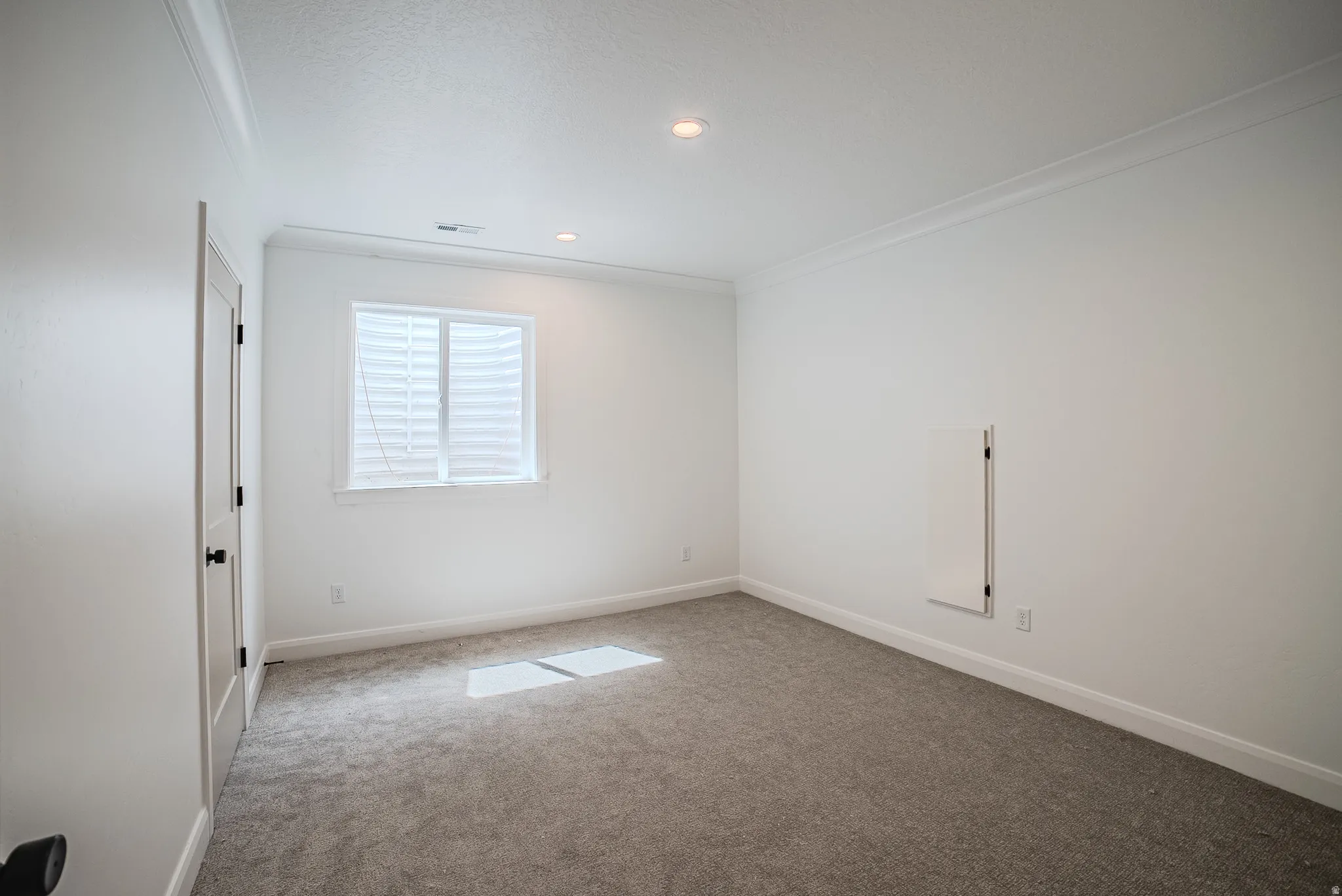 Plush carpet flooring, recessed ceiling lighting, crown molding, white trim, and a built-in access panel