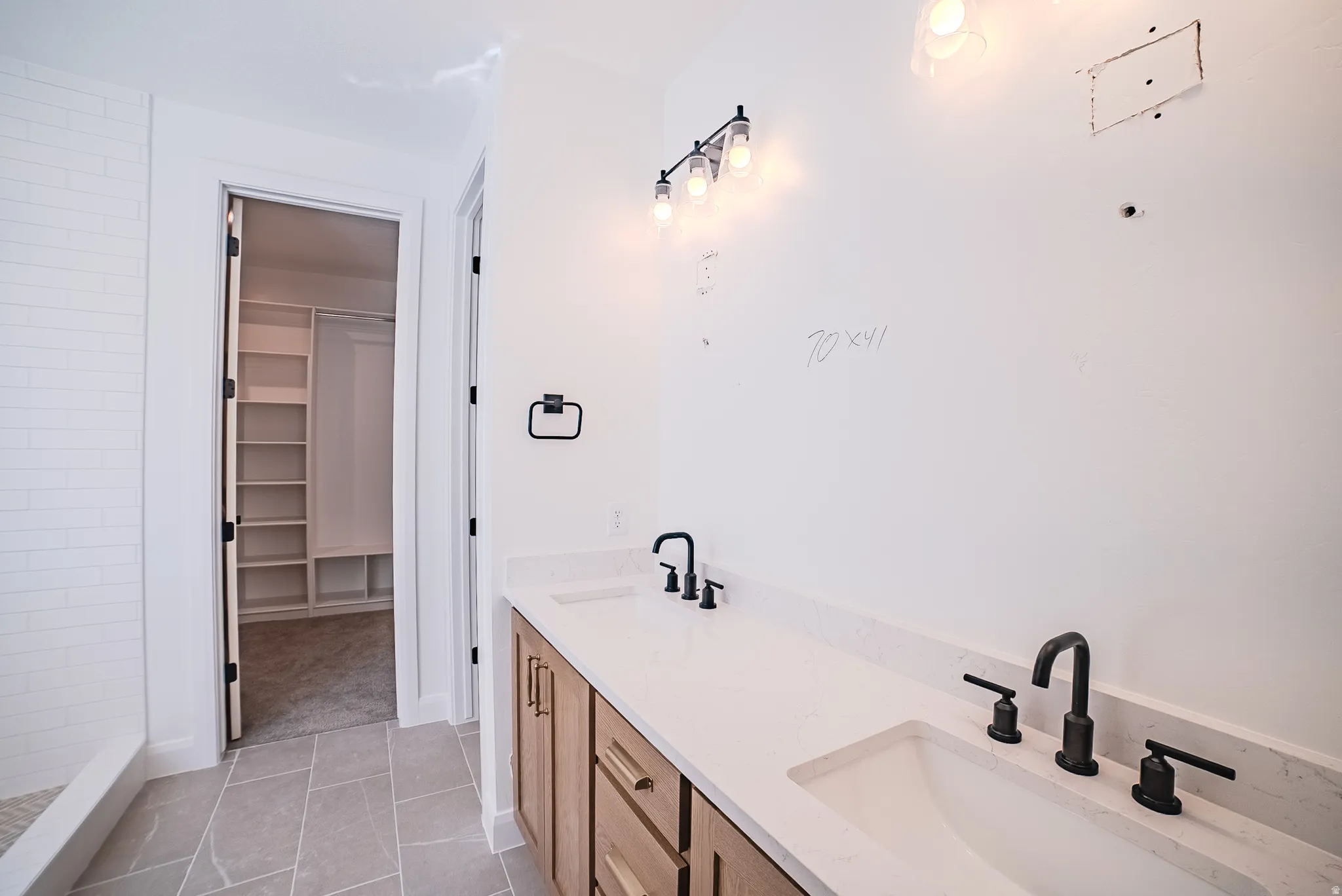 Dual vanity with integrated sinks, matte black fixtures, and wood-finish cabinetry