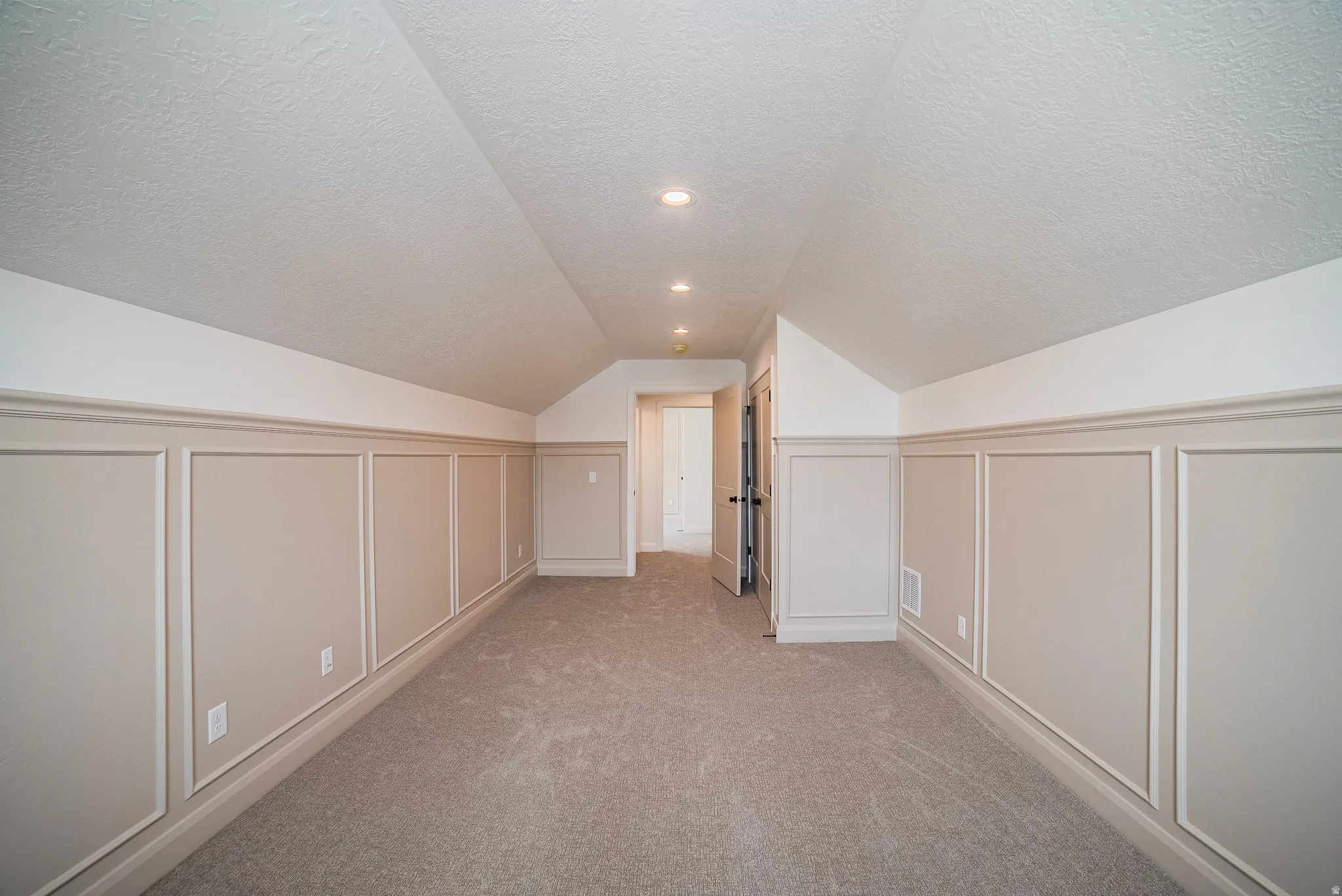 Sloped ceilings, recessed lighting, and wall paneling detail