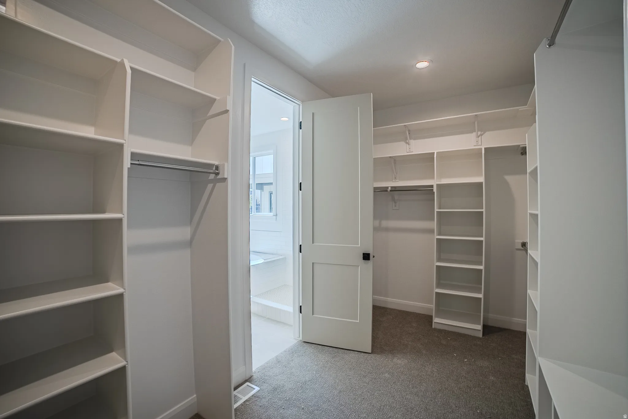 Walk-in closet featuring extensive built-in shelving, multiple hanging rods, and recessed lighting