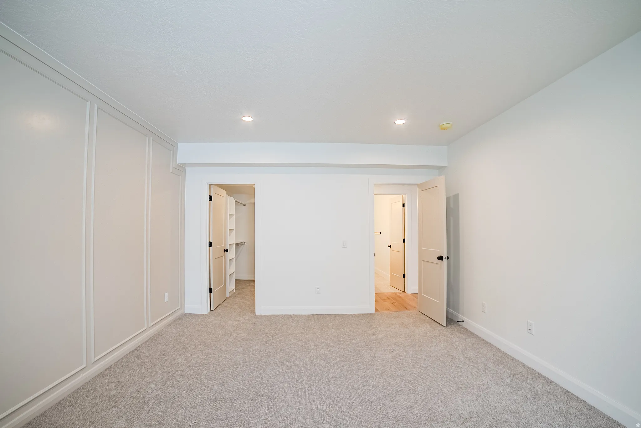 Built-in wall paneling, recessed lighting, and soft carpet flooring