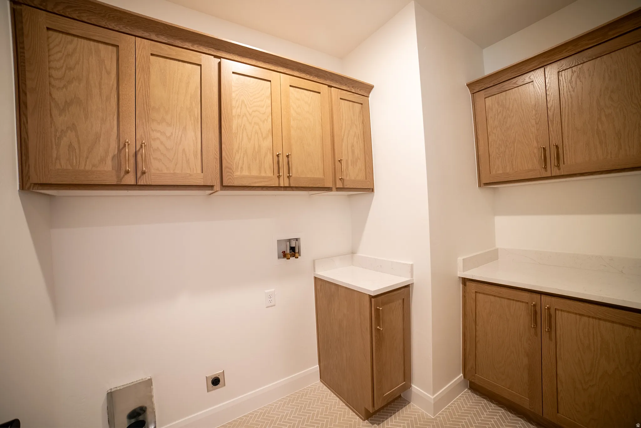 Extensive cabinetry with wood-finish doors, white countertops, and herringbone-pattern floor tiles