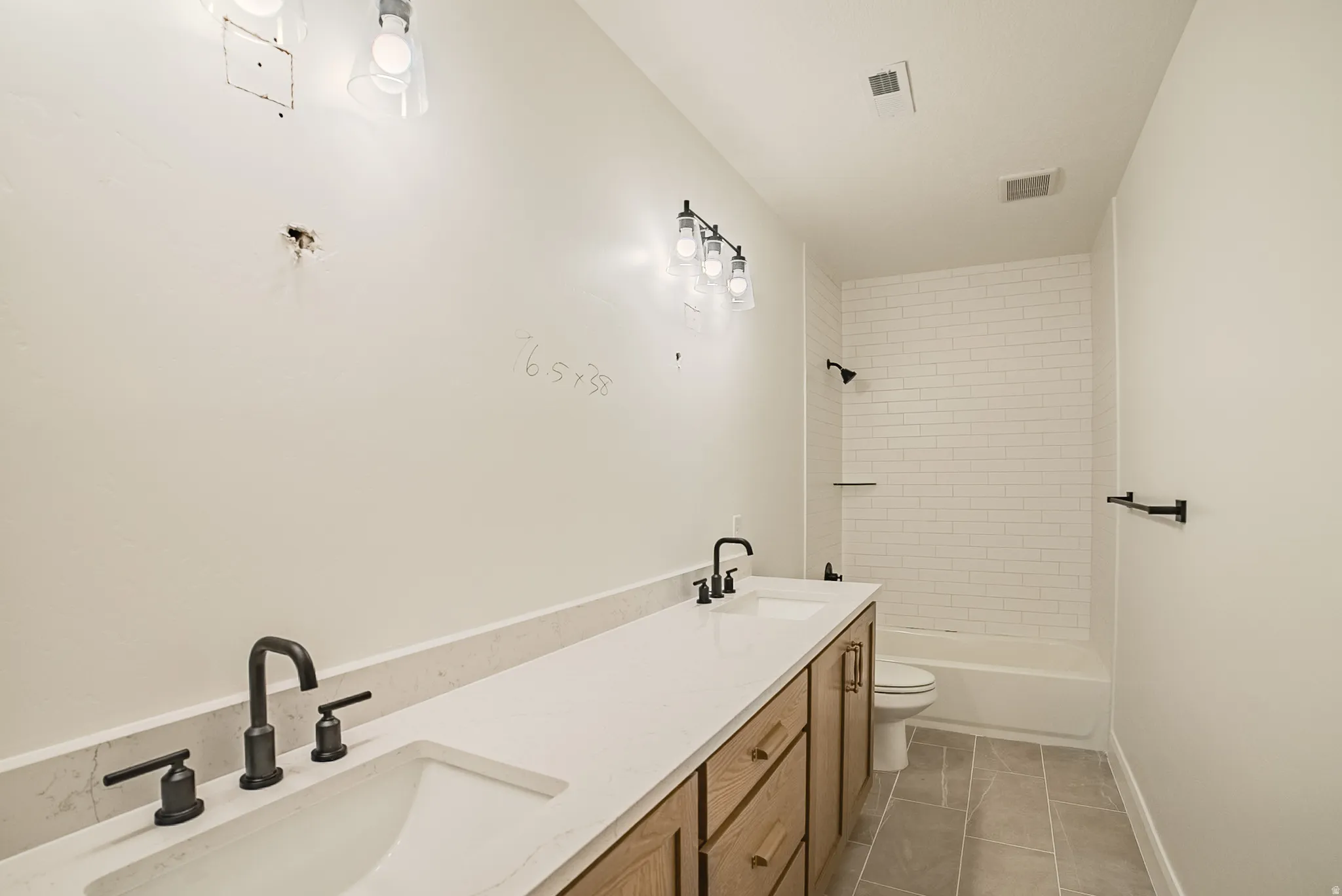Double vanity with white countertop, dual integrated sinks, matte black faucets, and wood-finish cabinetry