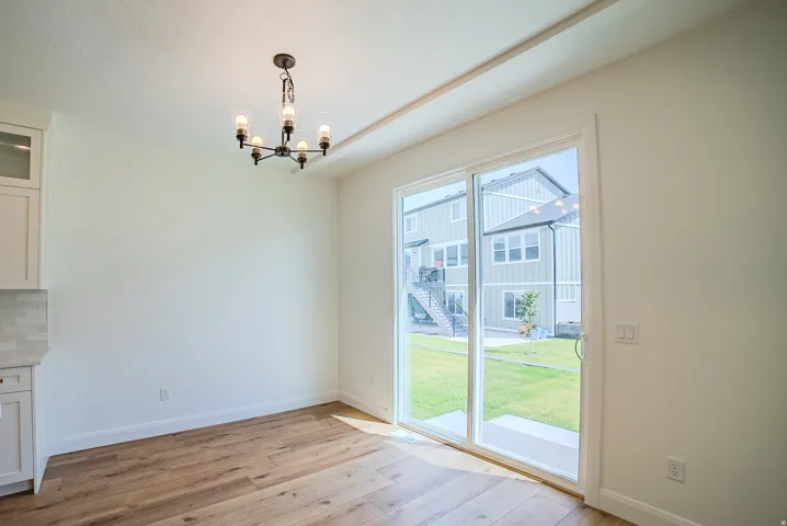 Wood-finish flooring, white walls, and a contemporary chandelier