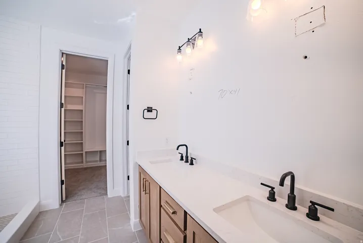Dual vanity with integrated sinks, matte black fixtures, and wood-finish cabinetry