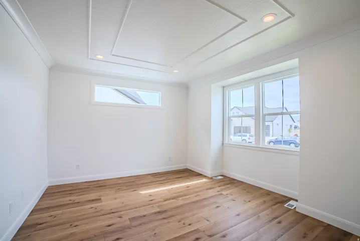 Coffered ceiling with recessed lighting, wood-finish flooring, large multi-pane window, and high rectangular accent window