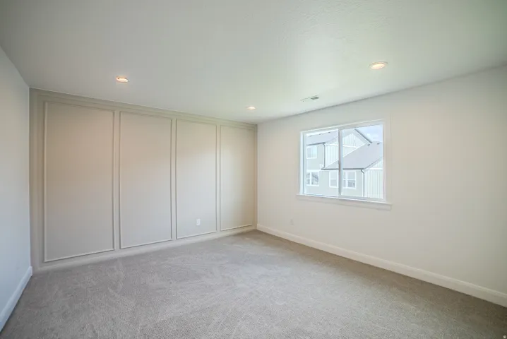 Recessed lighting, light gray carpeting, and an accent wall with decorative molding
