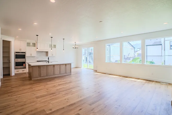 Spacious open-concept living area featuring wood-finish flooring, recessed lighting, and a kitchen island with a light-toned wood finish and a light-colored countertop