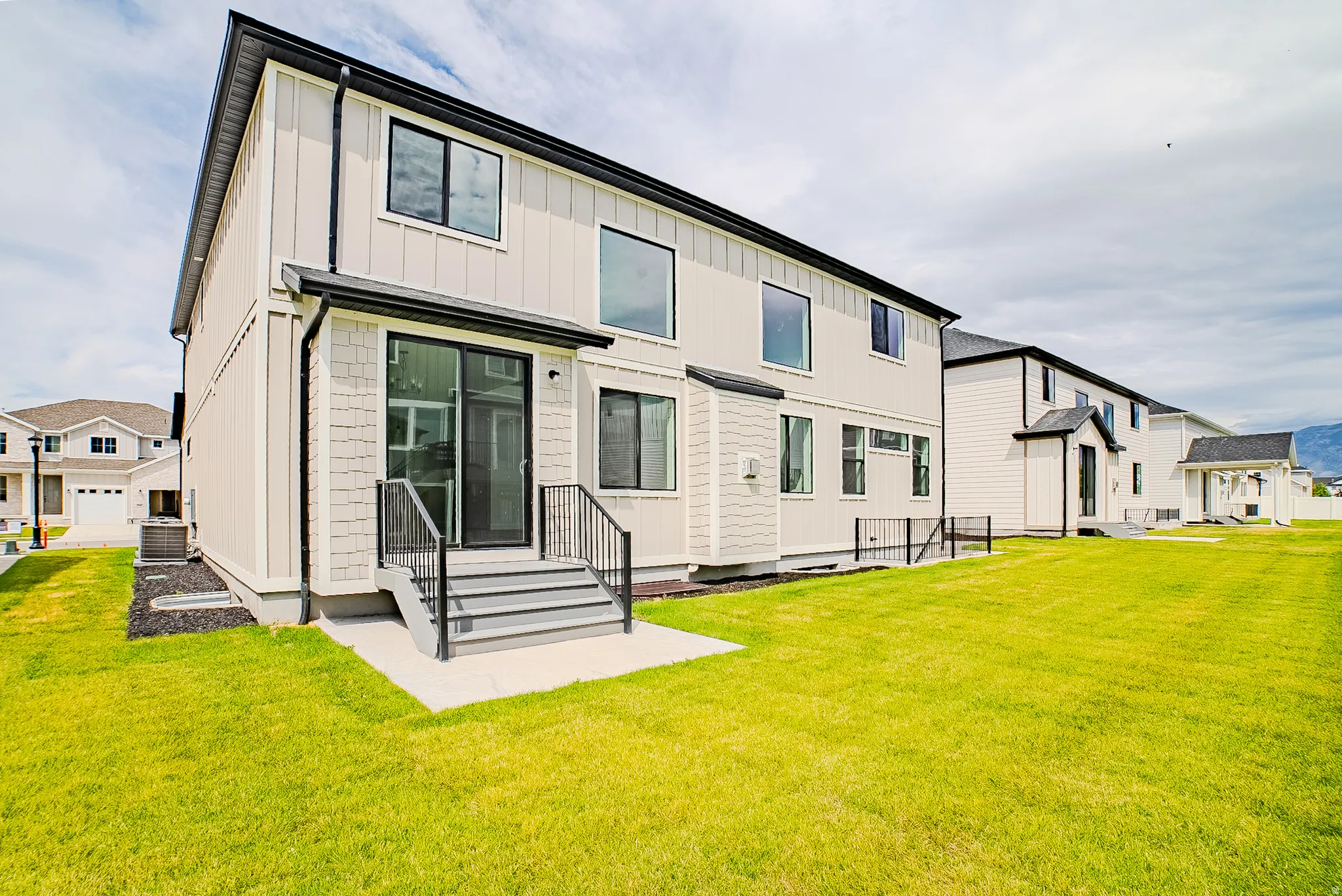 Exterior featuring vertical siding and shingle accents, black-framed windows, and a sliding glass door