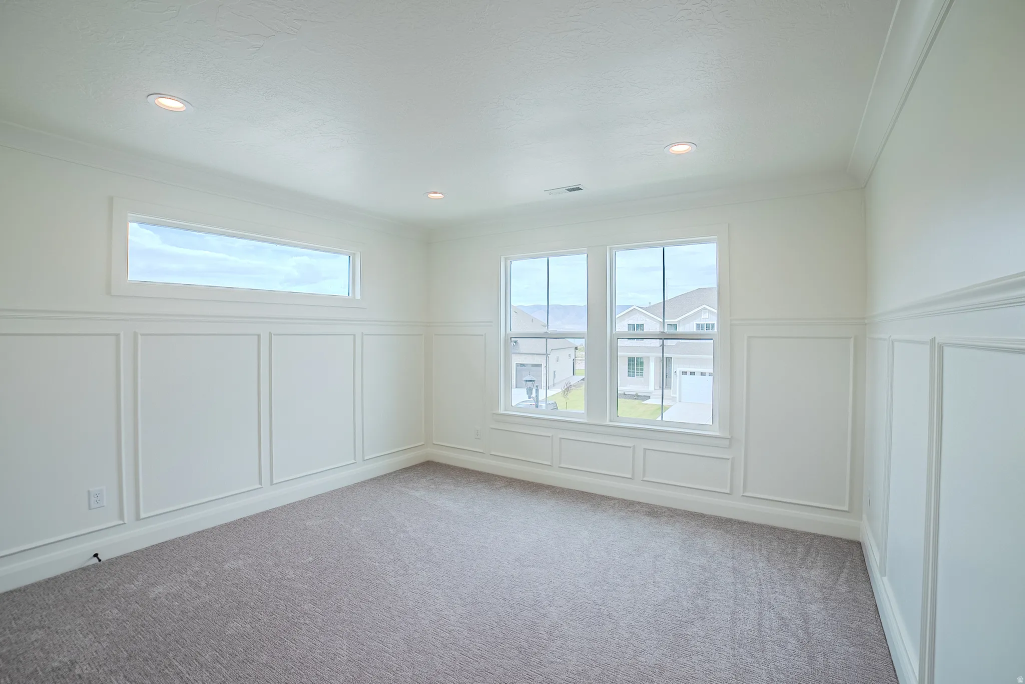 Recessed lighting, crown molding, white paneled wainscoting, and carpeted flooring