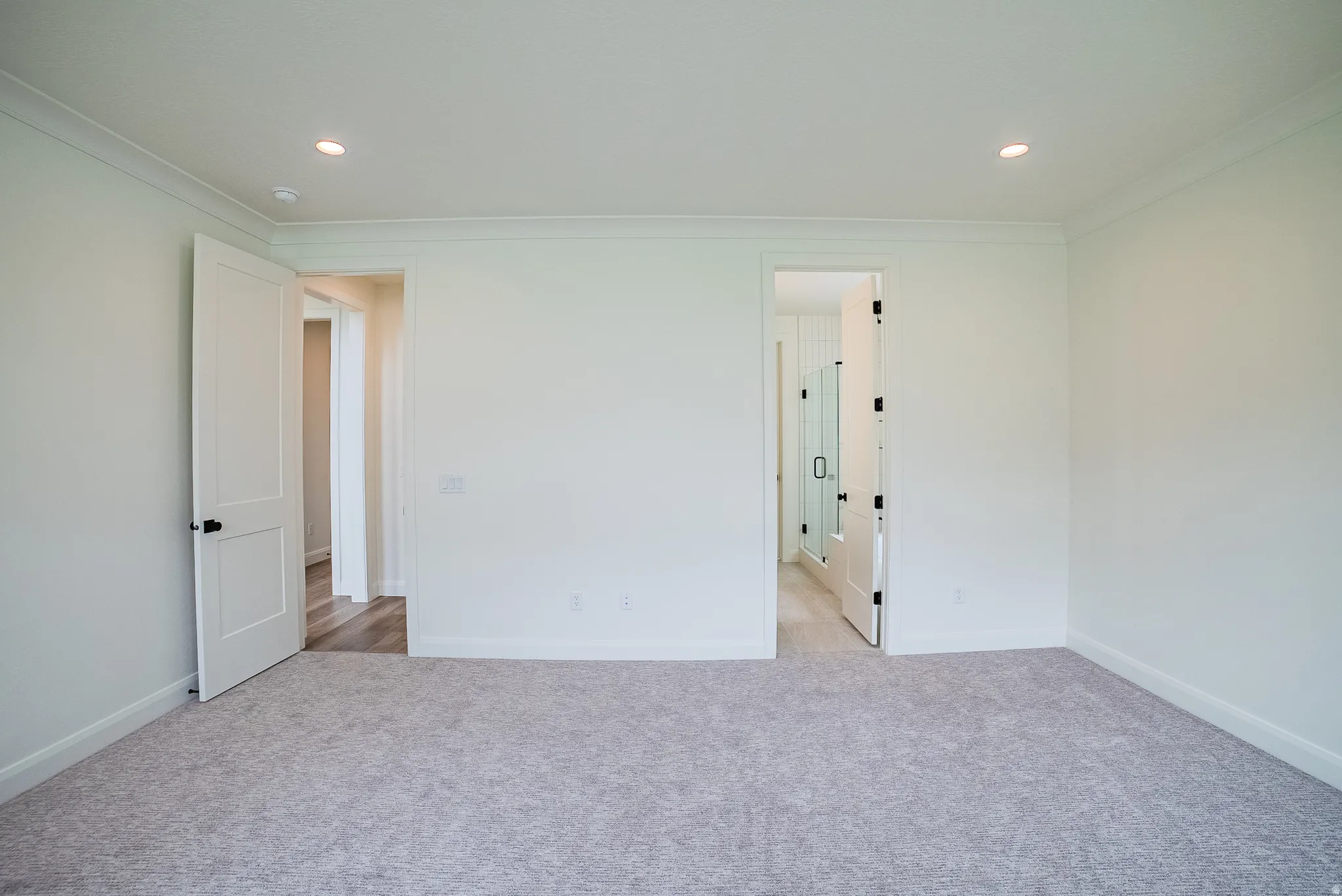Recessed lighting illuminates the neutral-toned walls and light-colored carpeting