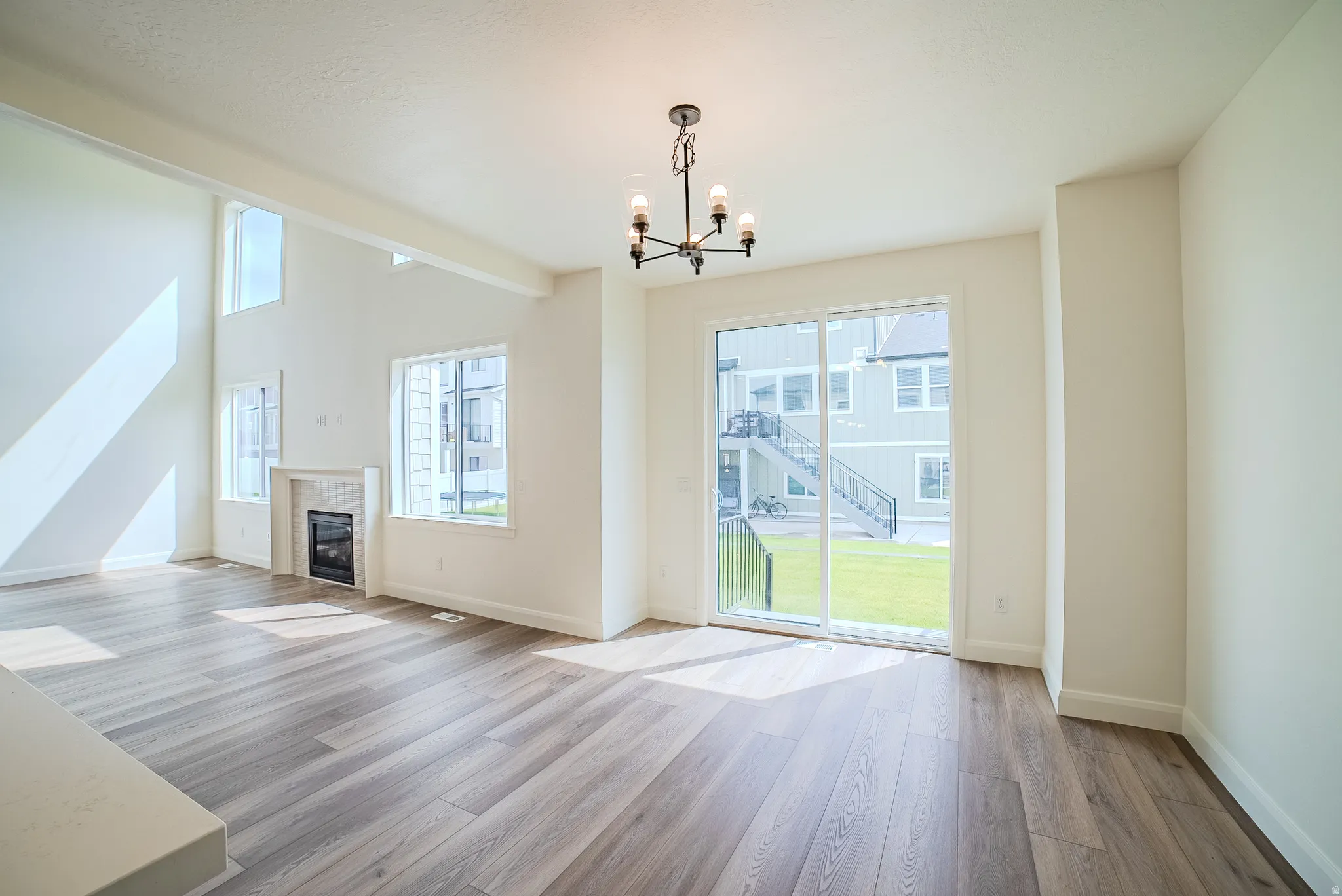 Wood-finish flooring, high ceilings, built-in fireplace, sliding glass door, and a black chandelier