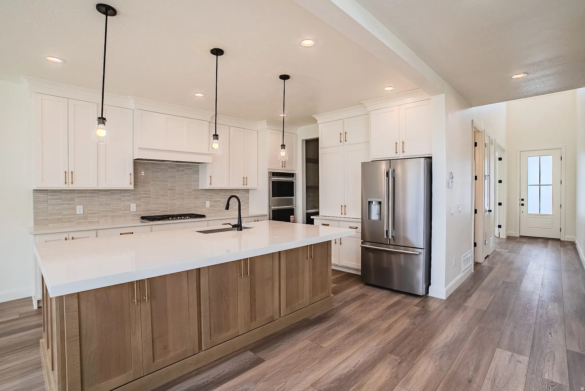 Kitchen featuring white cabinetry, a wood-finish island with a white countertop, and stainless steel appliances
