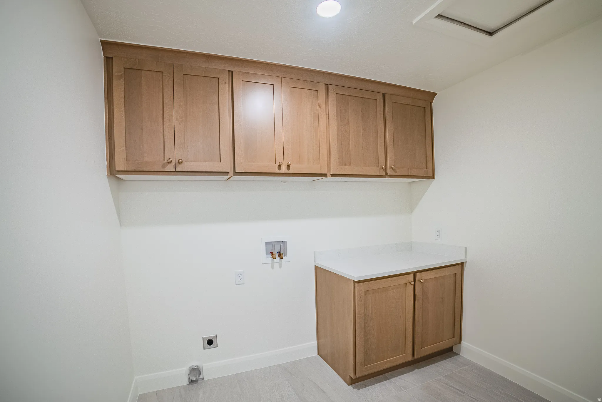 Light wood-finish cabinetry with gold-tone hardware, white countertop, and light wood-finish flooring