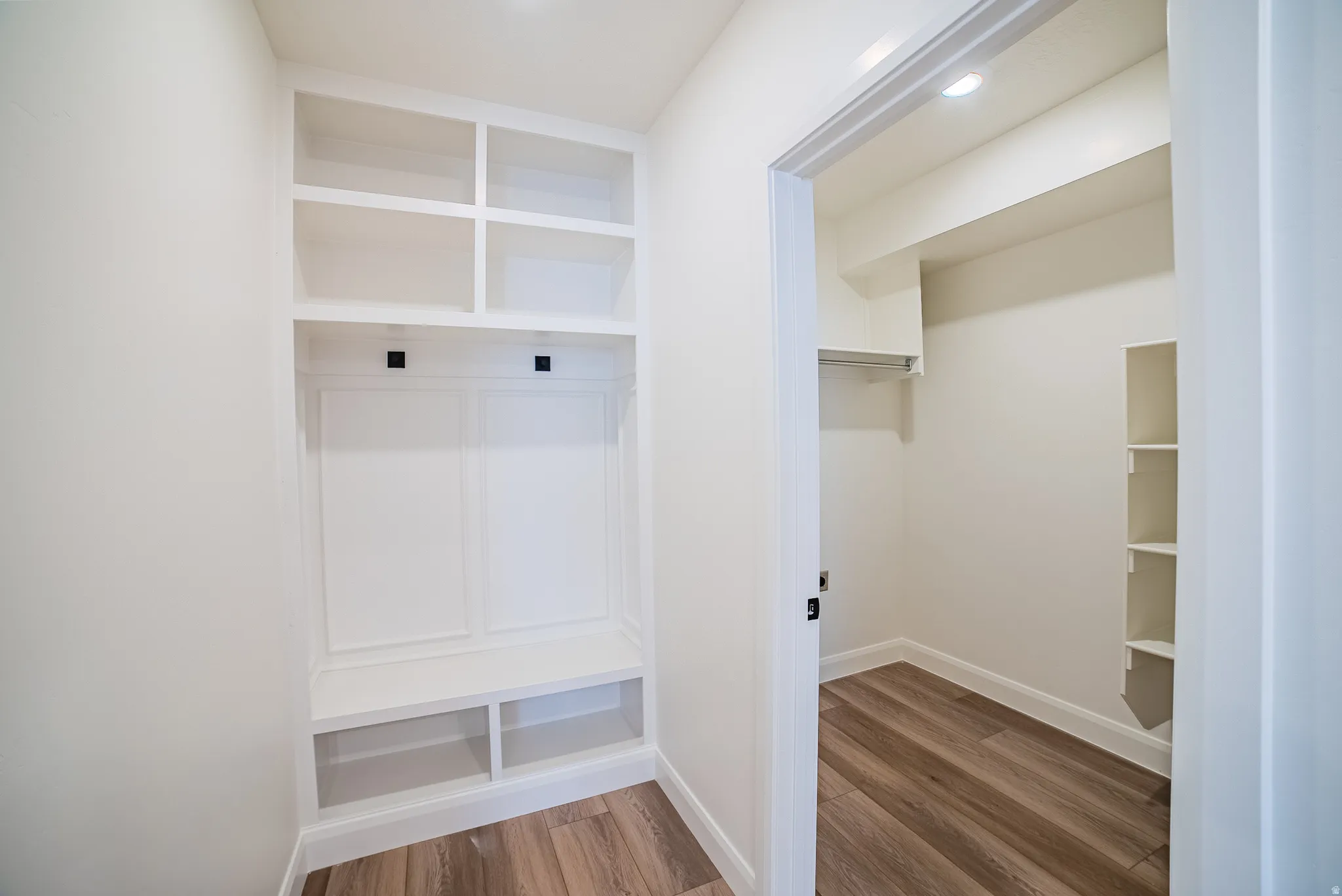 Built-in storage bench with open shelving, wood-finish flooring, and recessed ceiling lighting
