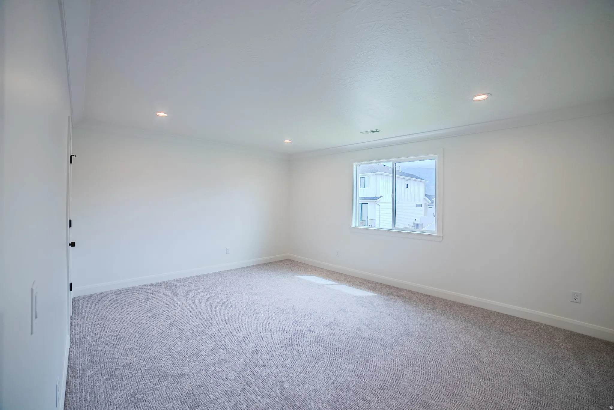 Recessed lighting, wall-to-wall carpeting, crown molding, white trim, and a sliding window