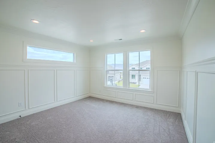Recessed lighting, crown molding, white paneled wainscoting, and carpeted flooring
