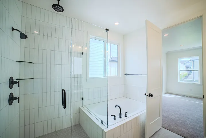 Walk-in shower with vertical subway tile, glass enclosure, and matte black fixtures