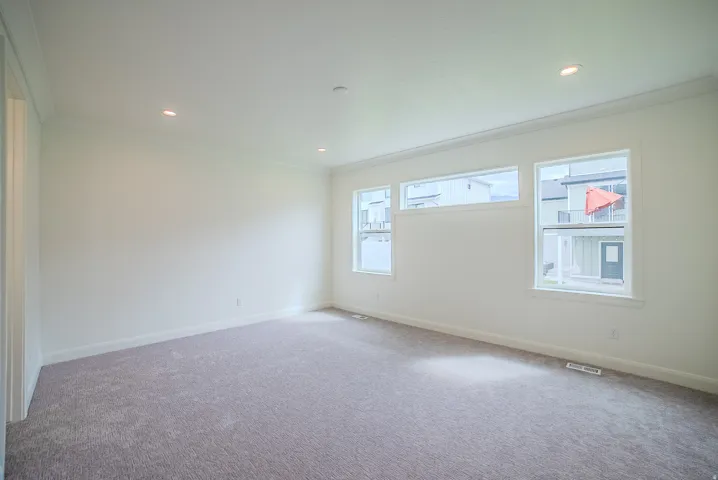Recessed lighting, crown molding, white trim, light gray carpeting, and multiple windows