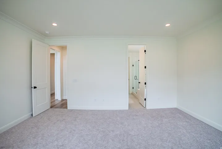 Recessed lighting illuminates the neutral-toned walls and light-colored carpeting