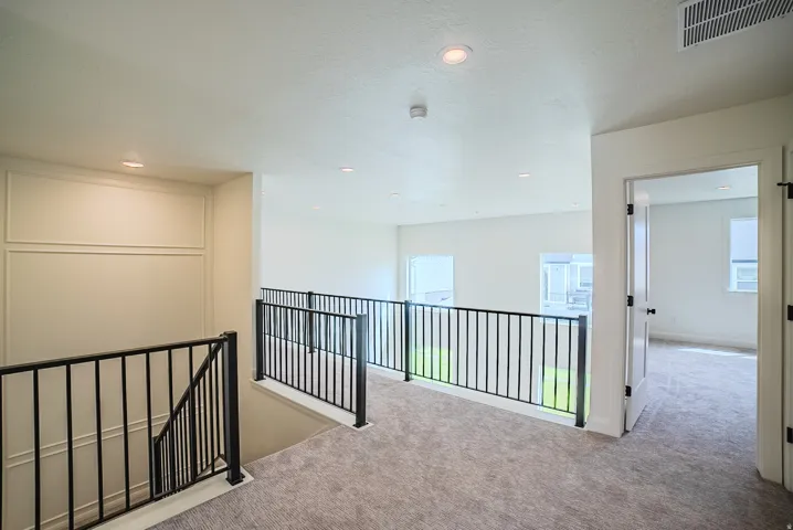 Spacious upper-level landing with carpeted flooring