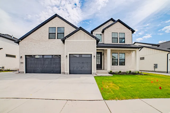 Contemporary two-story exterior with light-colored brick siding, dark-framed windows, and a covered front entry