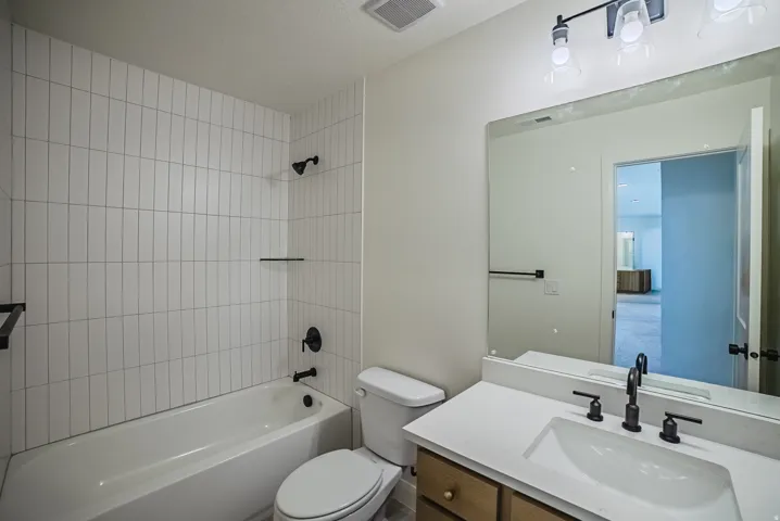 Bathroom featuring a white subway tile shower surround, bathtub, vanity with integrated sink, and black fixtures
