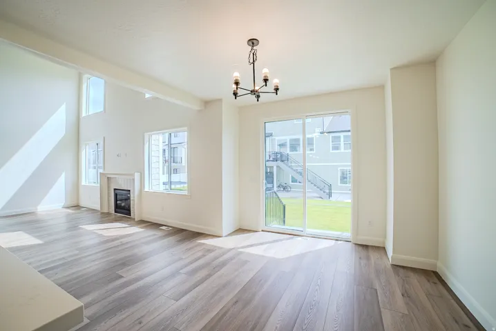 Wood-finish flooring, high ceilings, built-in fireplace, sliding glass door, and a black chandelier