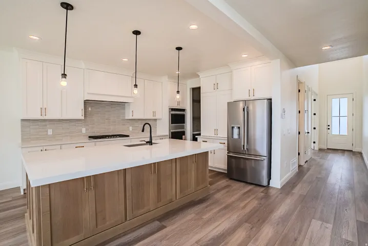 Kitchen featuring white cabinetry, a wood-finish island with a white countertop, and stainless steel appliances