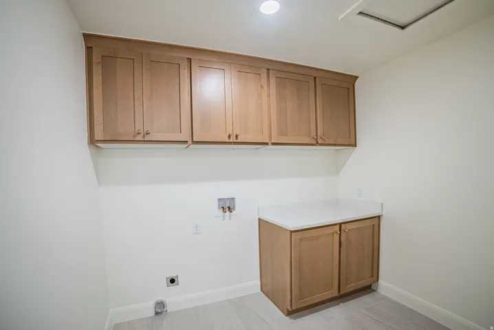 Light wood-finish cabinetry with gold-tone hardware, white countertop, and light wood-finish flooring