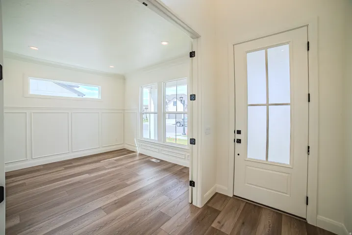Entryway featuring wood-finish flooring, a white paneled door with frosted glass inserts, and matte black door hardware