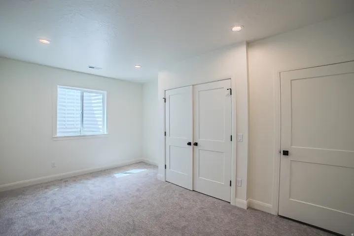 Recessed lighting illuminates the room with neutral carpeting