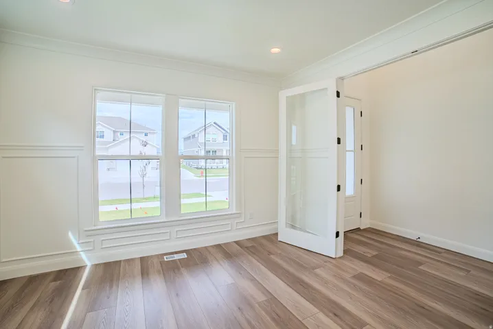 Wood-finish flooring, wainscoting, double windows, recessed lighting, and a frosted glass panel door