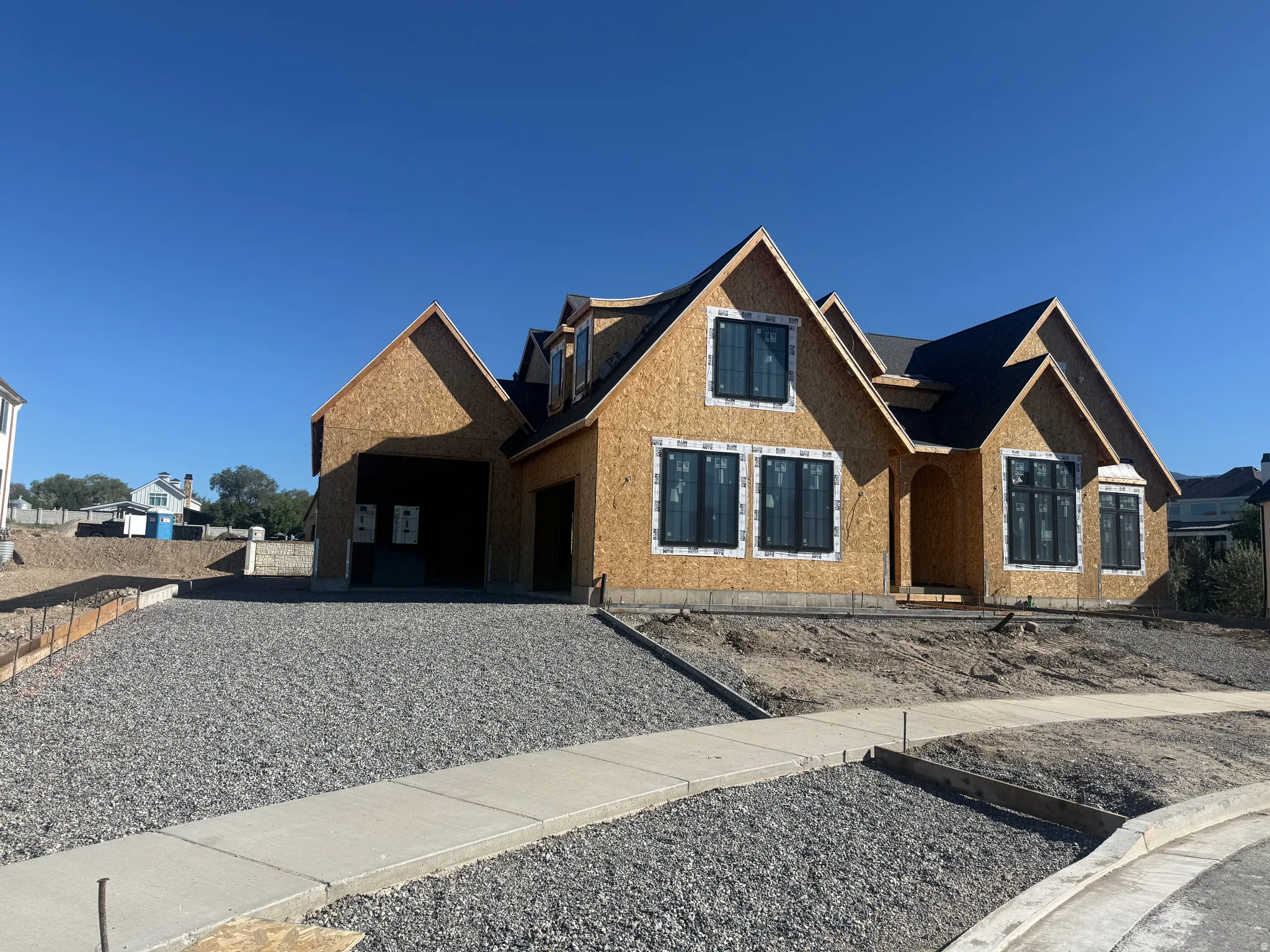 Newly constructed residence featuring multiple gables, black-framed windows, an arched entryway, and a concrete walkway