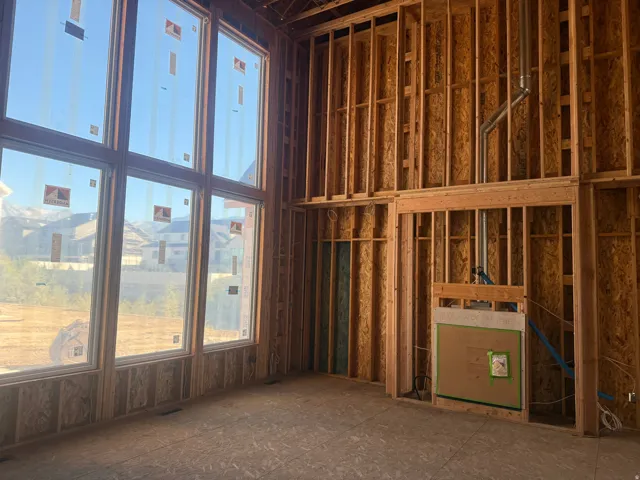 Two-story window wall, structural framing, integrated fireplace rough-in, and plumbing lines
