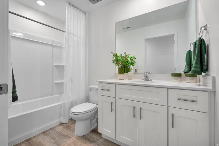 White vanity with brushed nickel hardware, integrated sink, and a large wall-mounted mirror