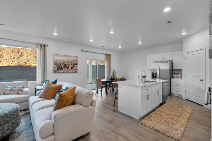 Open-concept living area with wood-finish flooring, recessed lighting, and a sliding glass door