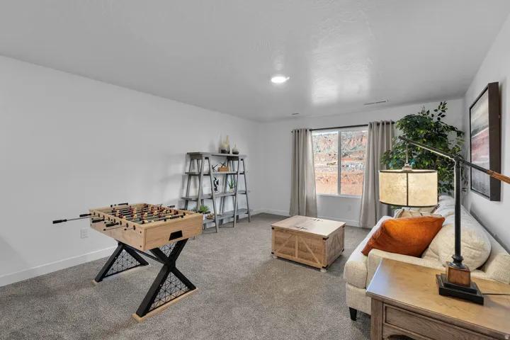 Carpeted floor, recessed lighting, and a large window with roller shades