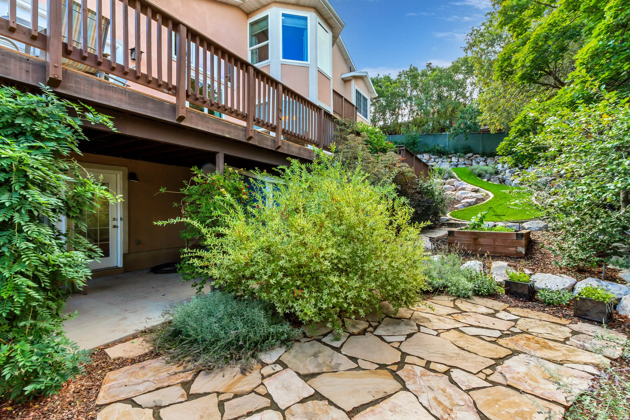 Expansive multi-level backyard featuring natural stone patio, manicured lawn, and mature landscaping