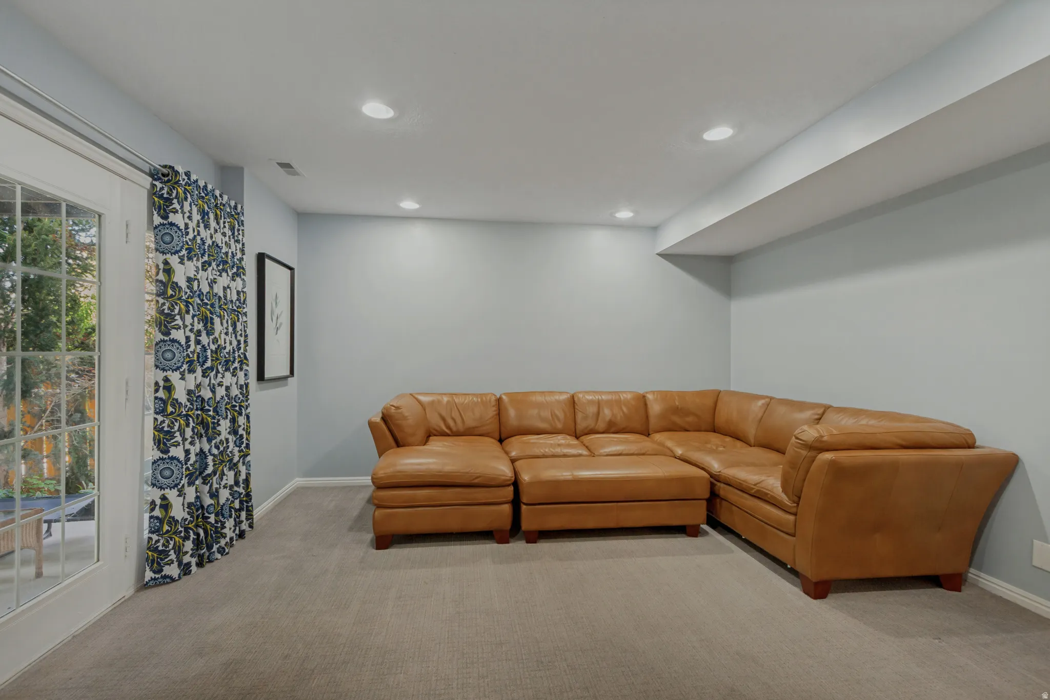 Recessed lighting, light-colored carpeting, and a glass-paned door