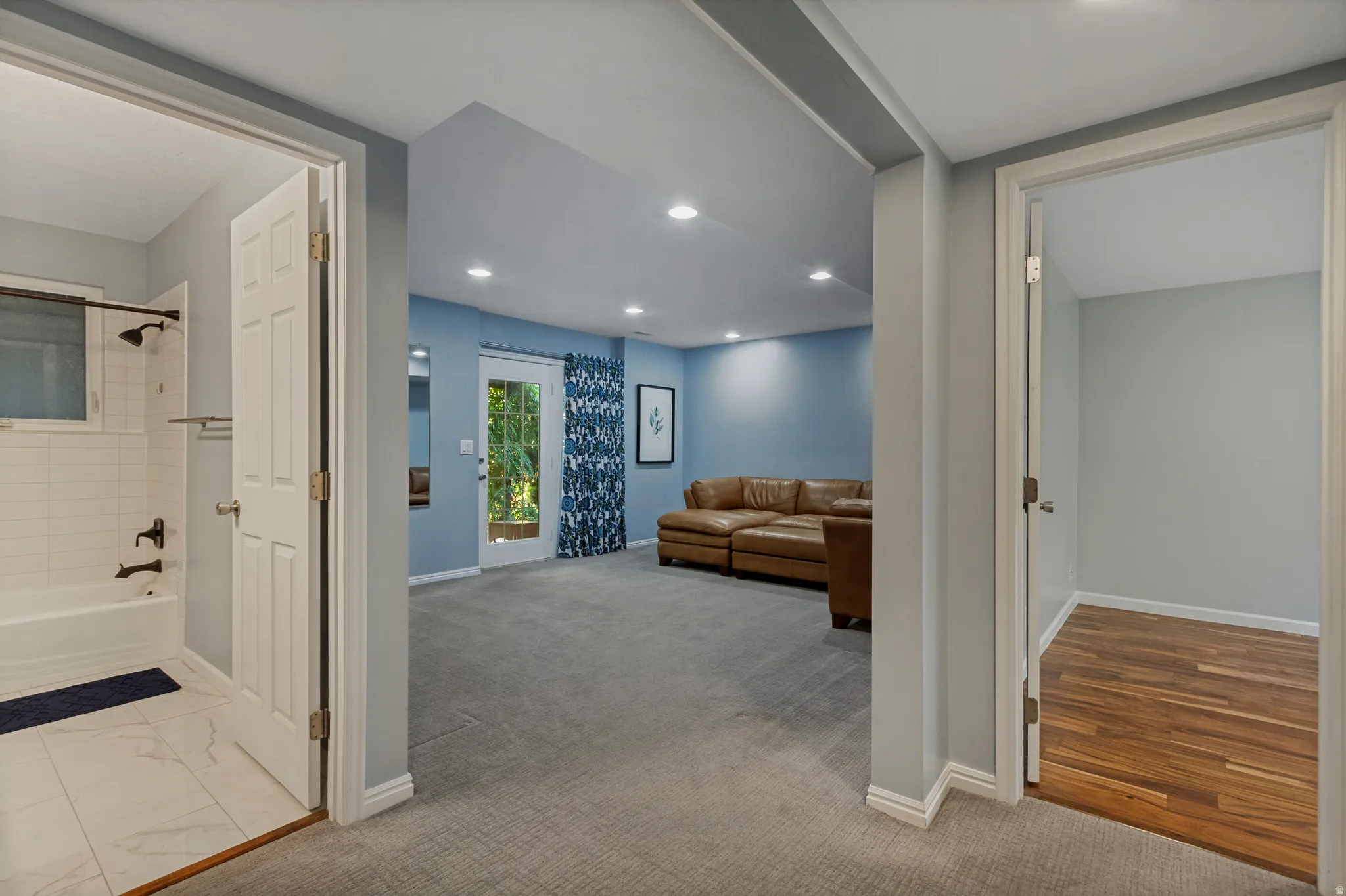 Recessed lighting, light blue wall paint, gray carpet, white tile flooring, and wood-finish flooring