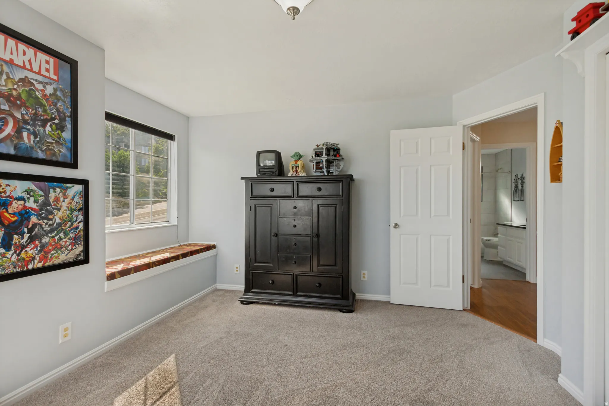 Window with integrated bench seating, neutral carpeting, light wall tones, and interior paneled door