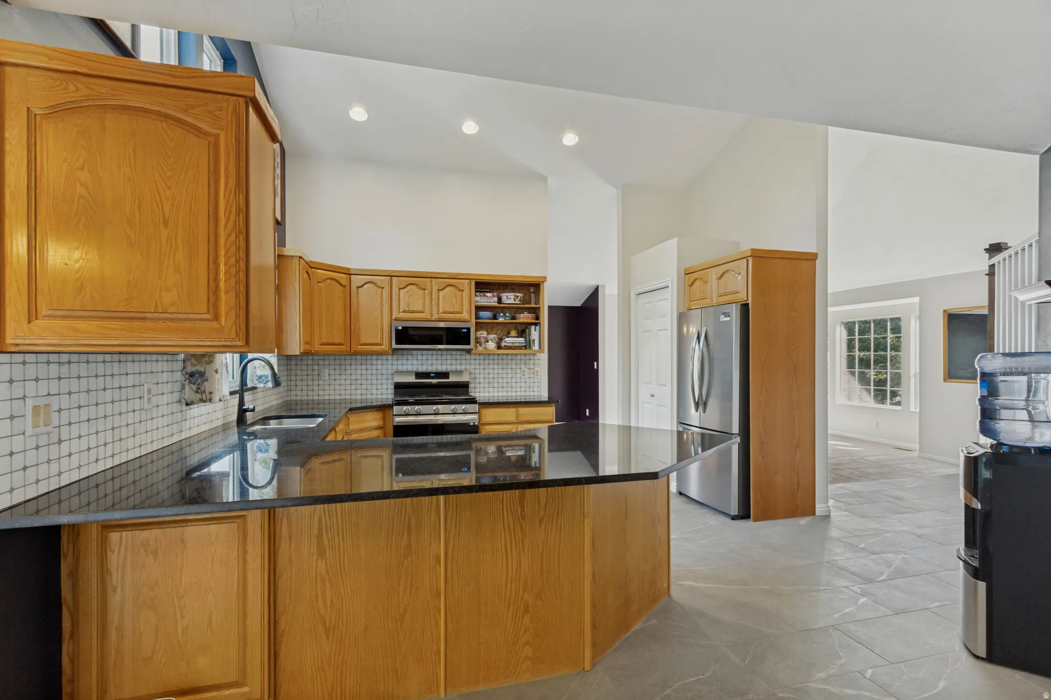 Kitchen featuring wood cabinetry, dark countertops, a tiled backsplash, and stainless steel appliances