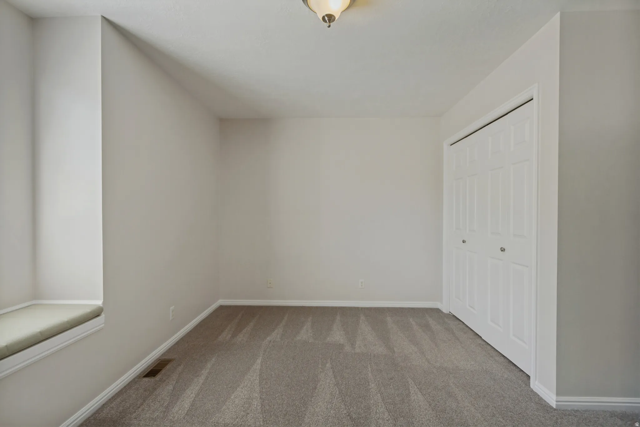 Neutral wall tones, patterned carpet, window seat, and bi-fold closet doors