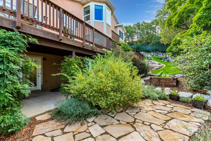 Expansive multi-level backyard featuring natural stone patio, manicured lawn, and mature landscaping