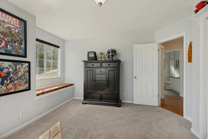 Window with integrated bench seating, neutral carpeting, light wall tones, and interior paneled door
