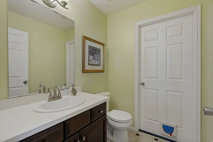 Vanity with a white countertop and dark wood-finish cabinetry, an undermount sink with a brushed nickel faucet, and a wall-mounted mirror