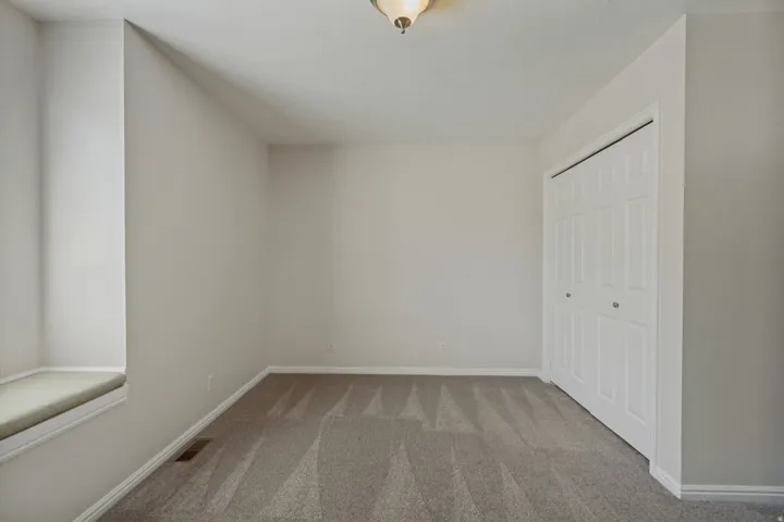 Neutral wall tones, patterned carpet, window seat, and bi-fold closet doors