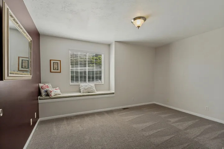 Recessed window seat with cushion, window with horizontal blinds, overhead ceiling light fixture, and neutral carpet