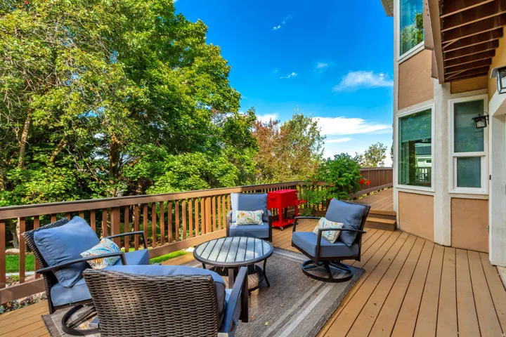 Expansive outdoor deck featuring wood-finish flooring, a wood-rail railing, exterior lighting fixtures, and a bay window